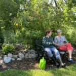 Two senior women sitting on a bench outside at Evergreen Retirement Community.